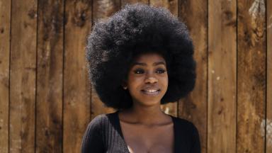 Woman smiling in front of wood-panelled wall